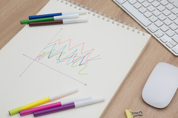 Drawing a graph of growth in a notebook on your desk at home.Wooden work table