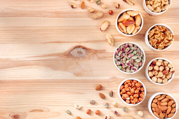 Nuts, overhead flat lay shot on a wooden table with a place for text. Healthy vegan snacks