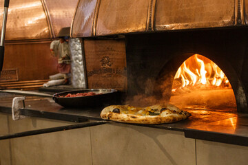 Pizza napoletana mentre viene sfornata da un forno a legna tradizionale