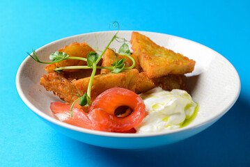 Closeup of freshly fried potato pancakes served with salmon fish and sauce.
