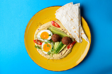Healthy breakfast with fresh boiled eggs, cut cucumbers, sauce and lavash bread.