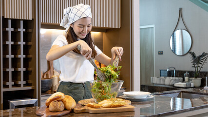 Asian woman making vegetable salad in her home kitchen, Vegetables contain a wide variety of...