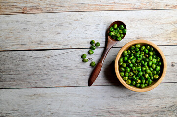 Top Views of Green Peas in a wooden bowl and wooden spoon isolated on the wooden background, Healthy Food Concept.