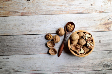 Top Views of Walnuts in a wooden bowl and wooden spoon isolated on the wooden background, Healthy Food Concept.
