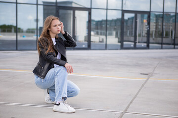 young teen girl walks around the city and the shopping center. white T-shirt and leather jacket.