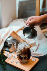 Fototapeta na wymiar Barista pouring milk into a glass of iced coffee