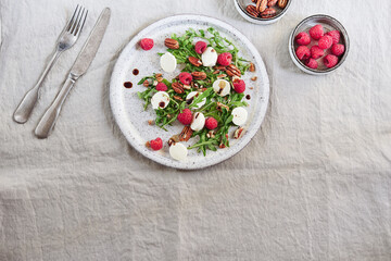 Summer salad with arugula, raspberries, mozzarella cheese and pecan nuts. Morning, breakfast, healthy food. Selective focus