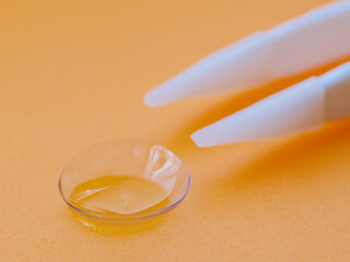 Tweezer holding contact lens. Selective focus.