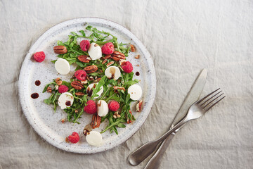 Summer salad with arugula, raspberries, mozzarella cheese and pecan nuts. Morning, breakfast, healthy food. Selective focus