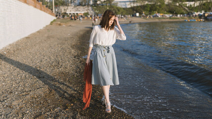 Woman in dress enjoys the sea shore.