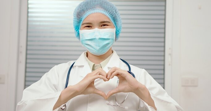 Young doctor woman, medical professional happy showing love with hands in heart shape expressing healthy and marriage symbol. Close up of man hands with heart. Romantic concept.