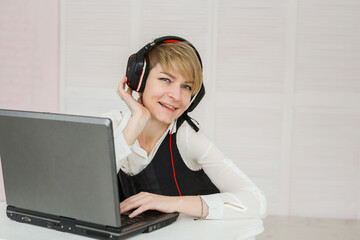woman works at a laptop, wearing headphones and a microphone for communication