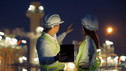 Two industrial engineer using digital tablet for work and discussing against the background of...