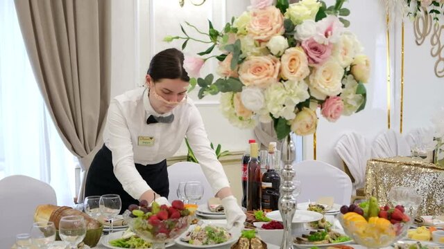Girl waiter sets the table on the table. 