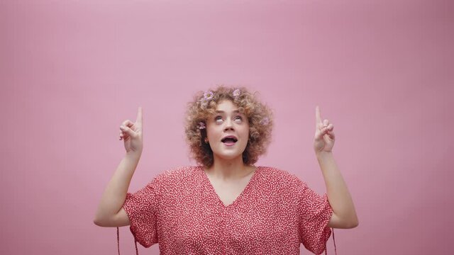 Happy young woman dancing with fingers pointed above her head with curly hair and flowers