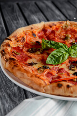 Fresh italian pizza with salami and black olives served over rustic wooden background. Traditional Italian pizza recipe