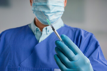 Close up of doctor's hand in medical gloves with a syringe ready for injection