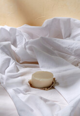 Fototapeta na wymiar natural cosmetics, hygiene and beauty concept - bar of craft soap on white sheet