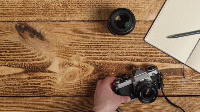 Top Down Shot of Person Picking Up SLR Camera from Table with Left Copy Space