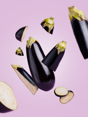 Fresh eggplants cut into pieces flying and levitate in the air against pastel violet background. Abstract or surreal vegetable motion composition. Creative healthy protein food concept.