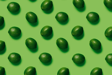 Geometrical pattern with limes isolated on a matching green background. Summer tropical fruit. Creative food concept. Flat lay, top view.