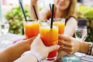 People clinking glasses with cocktail, aperol and wine on the summer terrace of cafe or restaurant....