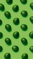 Geometrical pattern with limes isolated on a matching green background. Summer tropical fruit. Creative food concept. Flat lay, top view.