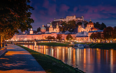 Fototapeta premium Wonderful evening scene of Salzburg city. View of the historical city, famous Hohensalzburg Fortress with reflection in the Salzach river, popular travel destination in Austria. Central Europe.