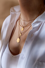 beauty, fashion and jewelry trends concept - close up of woman in white shirt wearing golden multi...