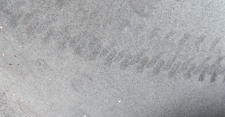 Car tire tread marks on the asphalt. The tread marks of a dark gray car tire are imprinted on the gray asphalt. Trace in a semicircular line of wide prints.