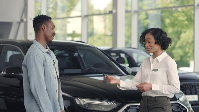 Car consultant presentating keys male client at salon