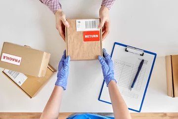Fotobehang health protection, delivery and mail service concept - customer making return of parcel or purchase and worker in protective gloves receiving box © Syda Productions