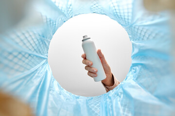 recycling, waste sorting and sustainability concept - hand throwing hair spray bottle into trash can