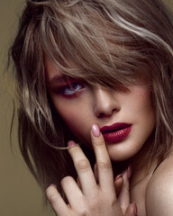Close-up of a woman's face. Thick bangs fall over the face and cover one eye. Red lipstick. The...