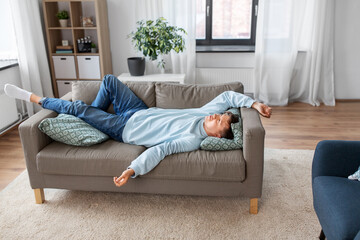 people, boredom and depression concept - bored or lazy young man lying on sofa at home