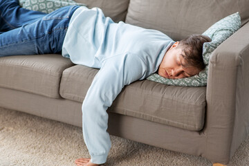 people, boredom and depression concept - lazy young man sleeping on sofa at home