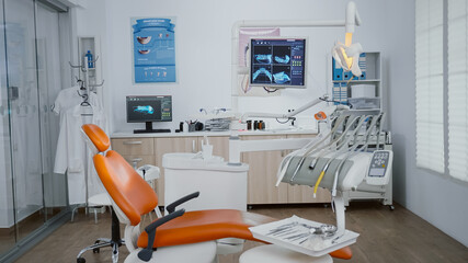 Revealing shot of stomatology chair with nobody in it, teeth diagnosis xray images on display. Medical clinic orthodontic empty room, ready for healdcare treatment, modern dentist office for oral care