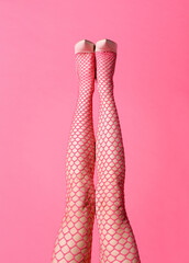 Sexy straight legs of a lady wearing pink fishnet stockings