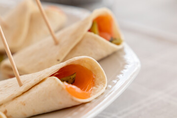 small rolls of thin pita bread with smoked salmon and sliced pickles