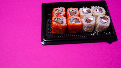 a small portion of rolls with fish on a pink background