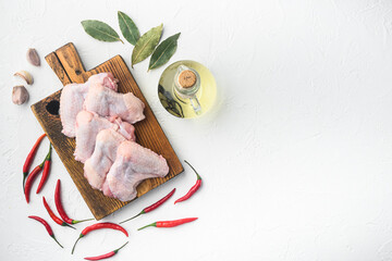 Uncooked chicken wings with spices, on wooden cutting board, on white background, top view flat...