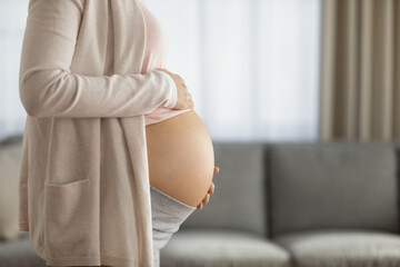 Side view close up cropped of pregnant woman touching belly tummy, feeling kicks, expecting baby, profile of young future mother standing at home, copy space, pregnancy and motherhood concept