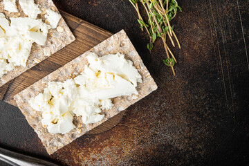 Crispbreads with feta, on old dark rustic table background, top view flat lay, with copy space for...