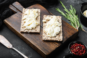 Wholegrain Rye Crispbread with cream cheese, on black dark stone table background