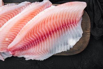 Raw white fish fillet, on black background, top view