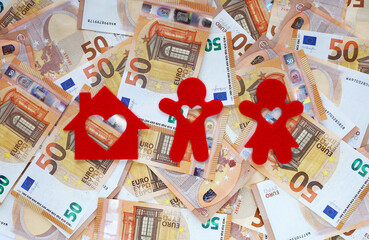 Red felt small house, silhouette of men and women with heart-shaped holes cut out in all of them on 50 fifty euro banknotes background. Home loan for a young couple. Money for family dream house.