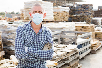 Man in protective mask of a hardware store keeps records of natural stone tiles