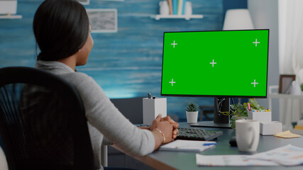 African american woman working remote from home listening school professor explaining online course. Student looking at mock up green screen chroma key display during virtual videocall meeting