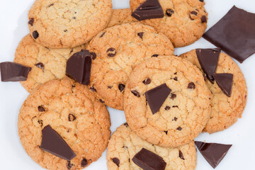 Chocolate chip cookies and broken chocolate pieces on white background