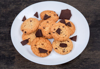 Chocolate chip cookies and broken chocolate pieces on white dish
